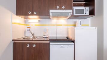 A compact kitchen with wooden cabinets, a microwave, a coffee maker, and a dishwasher.