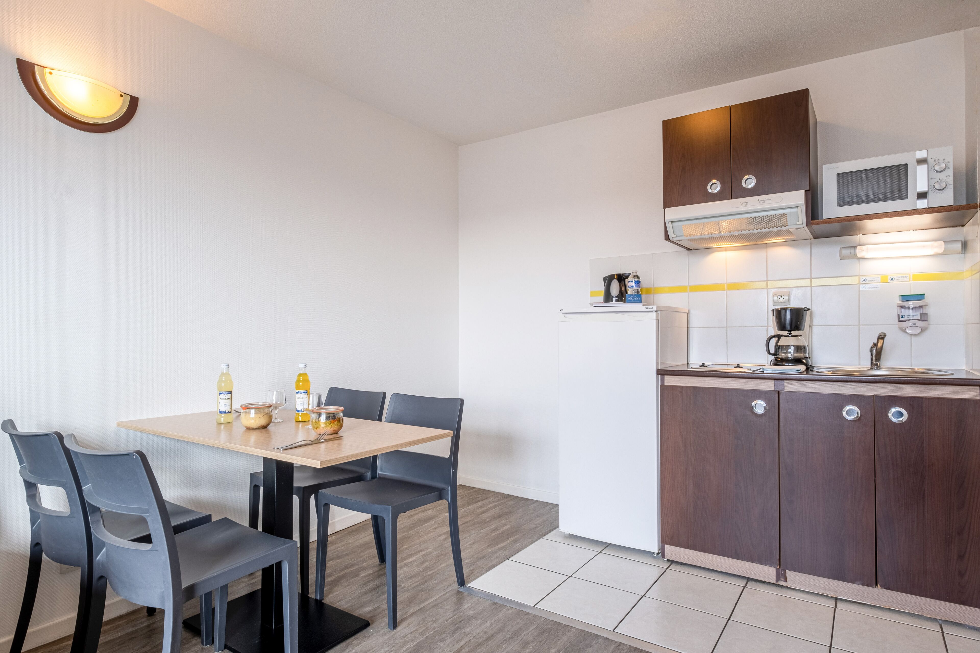 Una cocina compacta con microondas, cafetera y armarios.