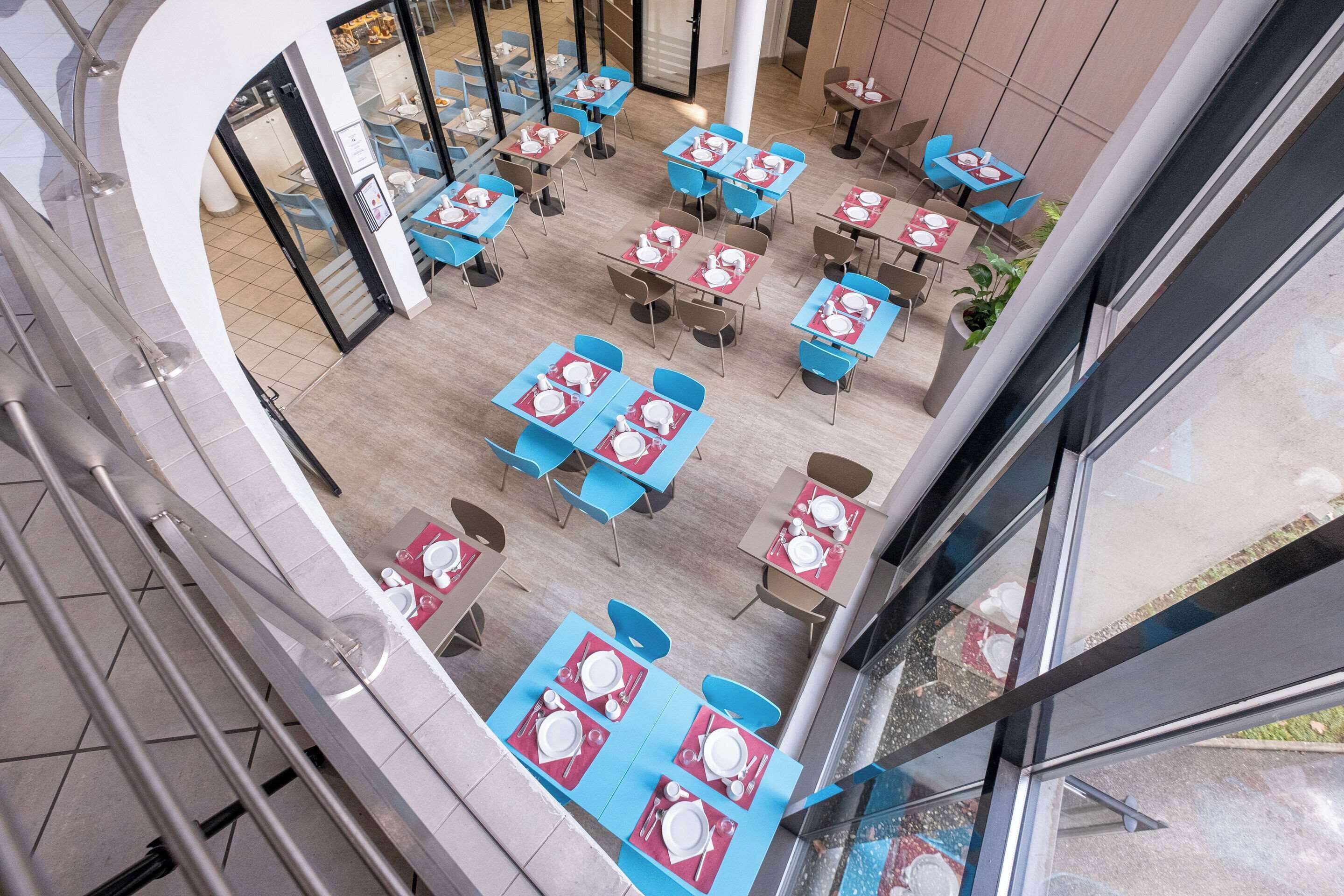 Un espace de restauration intérieur moderne, doté de nombreuses tables et chaises, disposées dans un aménagement spacieux.