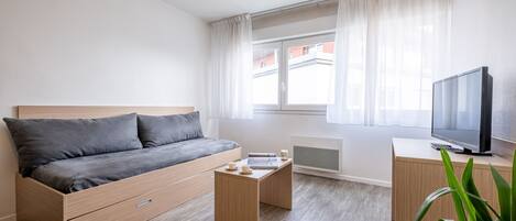 Et moderne soveværelse med seng, sengebord og fjernsyn.