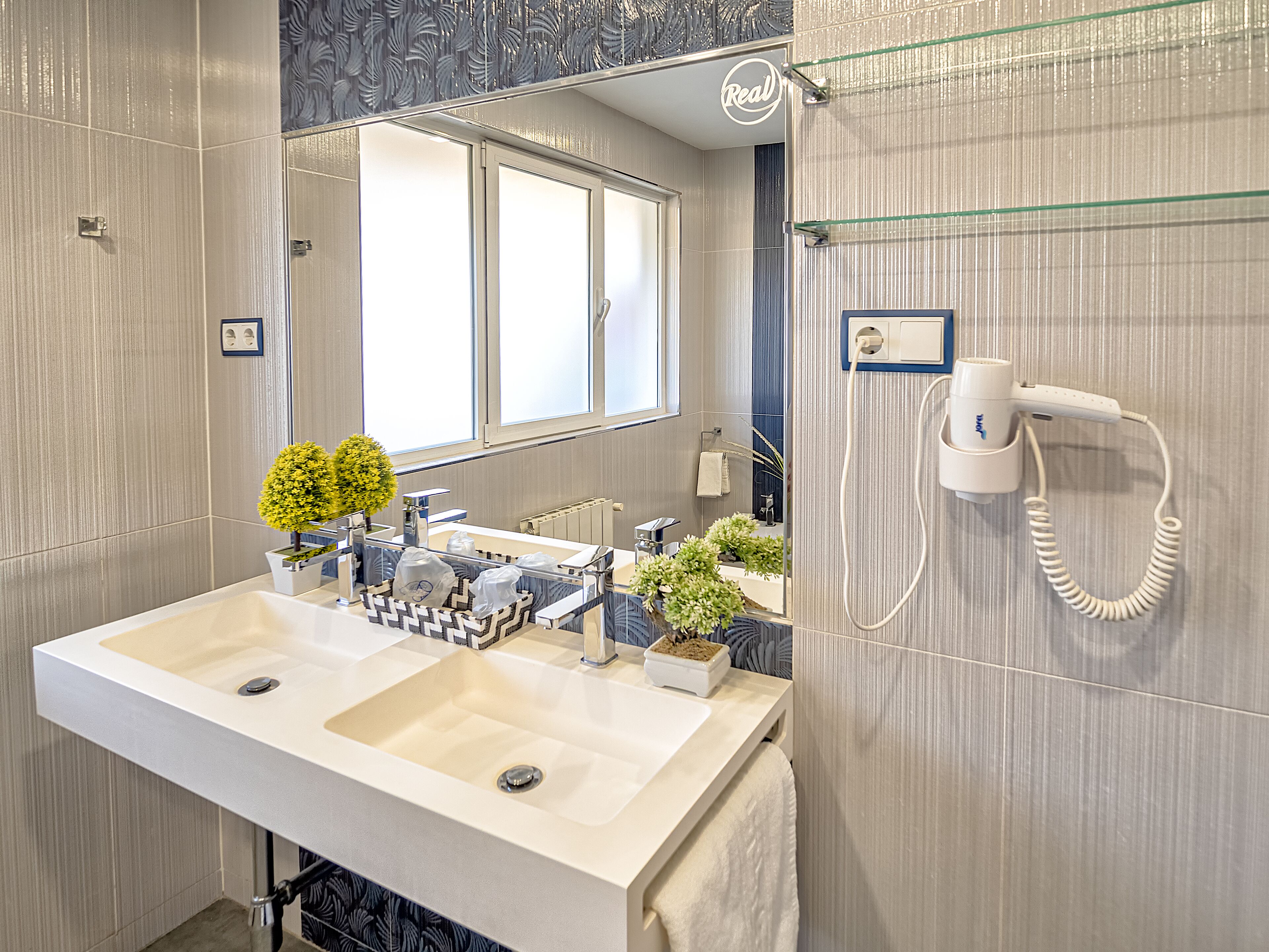 A modern bathroom with a large sink, a hairdryer, and a mirror.