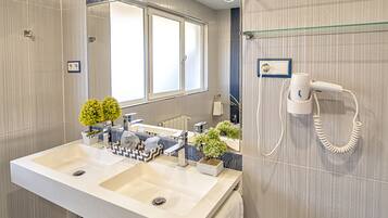 A modern bathroom with a large sink, a hairdryer, and a mirror.