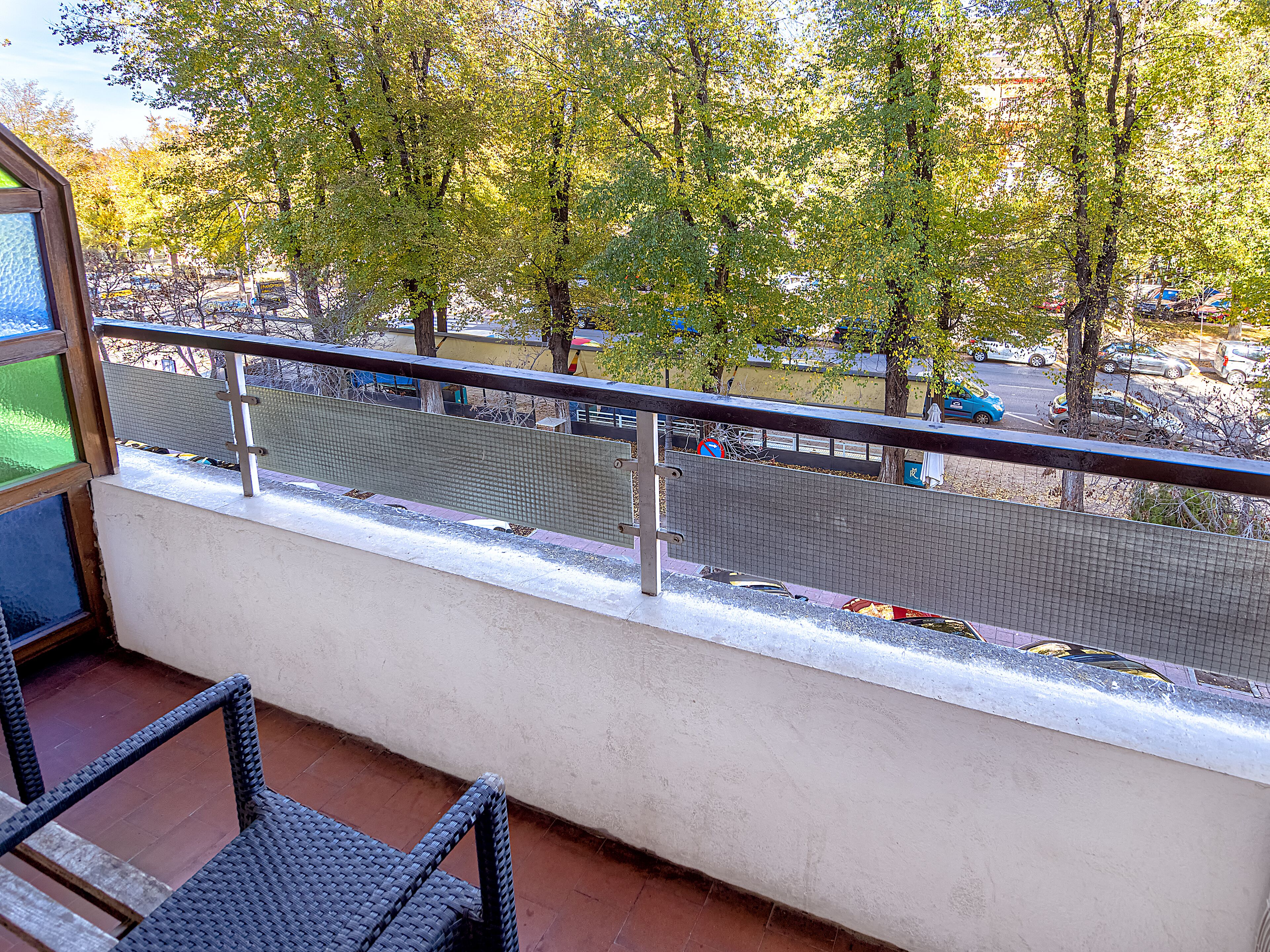 A balcony with a view of a parking lot and trees.