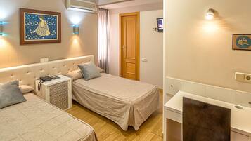 Een hotelkamer met twee bedden, een bureau, een stoel, een airconditioner, een schilderij en een deur.