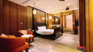 A hotel room with a large bed, a sitting area with a chair and a small table, a mirror, and a bathroom visible through an open door. - Region Motel (Lukang)