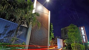 Een modern gebouw met verticale houten lamellen en een bord met de naam van een hotel.