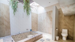 Een moderne badkamer met een groot bad, een aparte douche en een toilet.