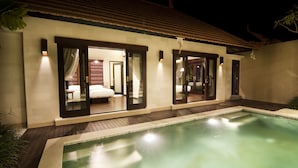 A modern hotel with a swimming pool, large windows, and a well-lit interior. - Villa Puspa (Tabanan)