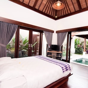 A bedroom with a bed, a TV, and a view of a swimming pool.