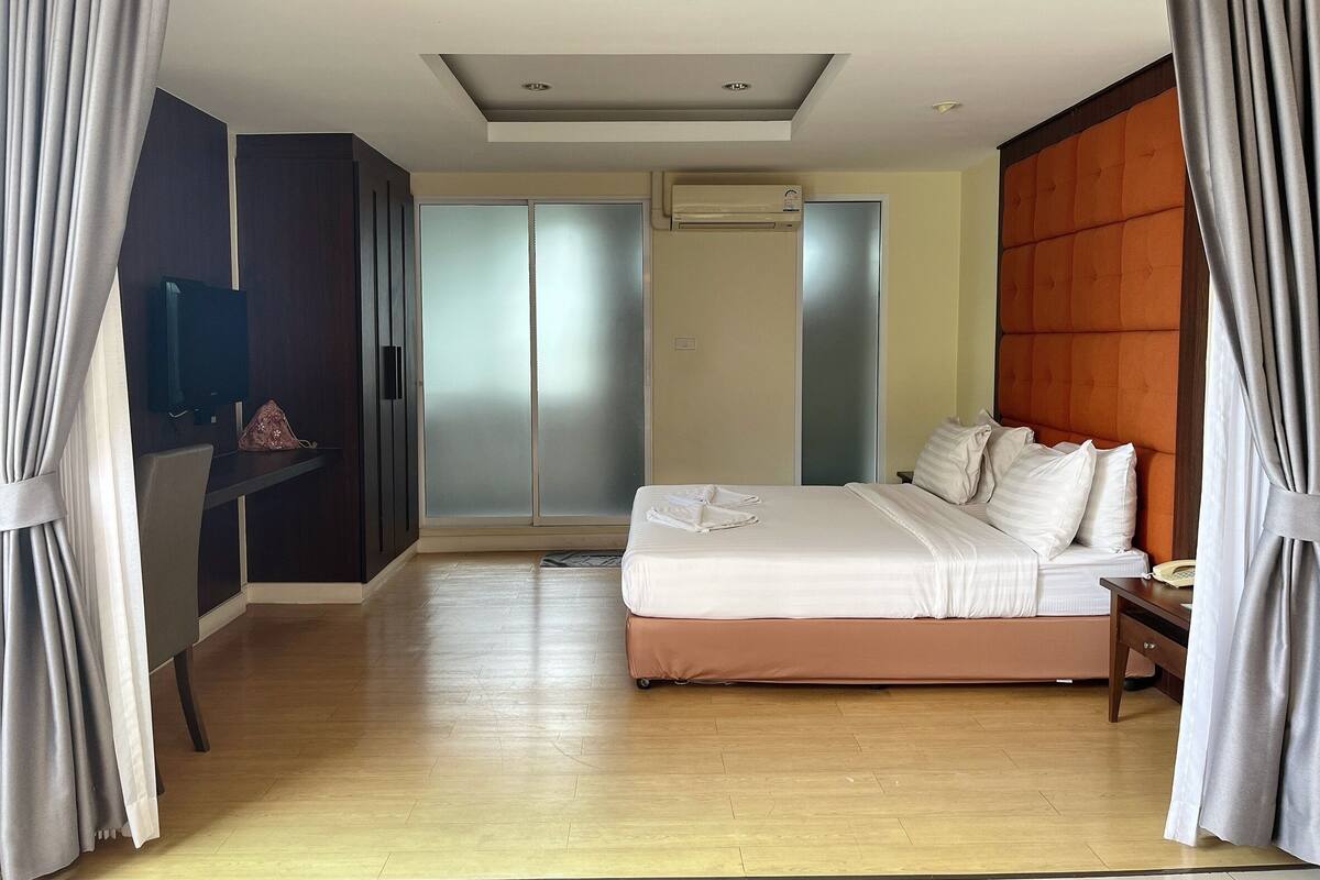 Een moderne hotelkamer met een bed, een televisie, een kledingkast en een schuifdeurkast.