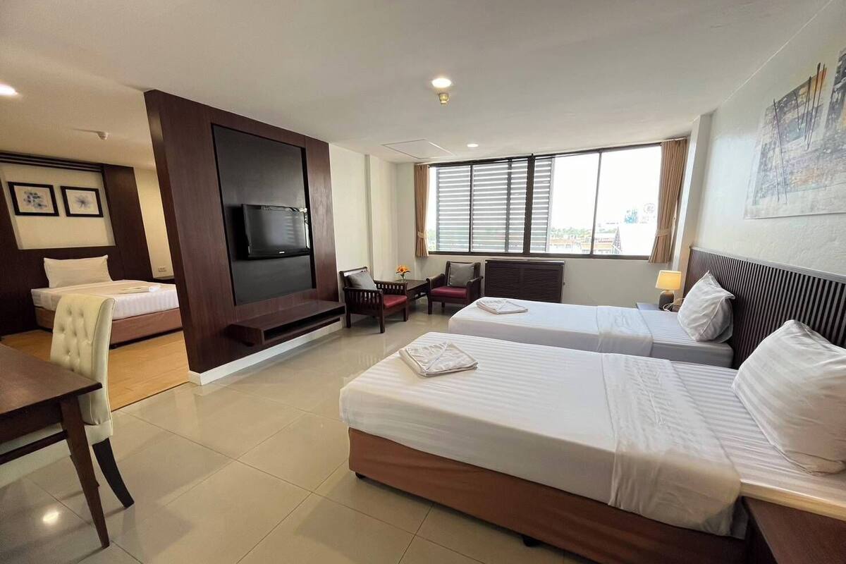 Een hotelkamer met twee bedden, een televisie, een bureau en een stoel.