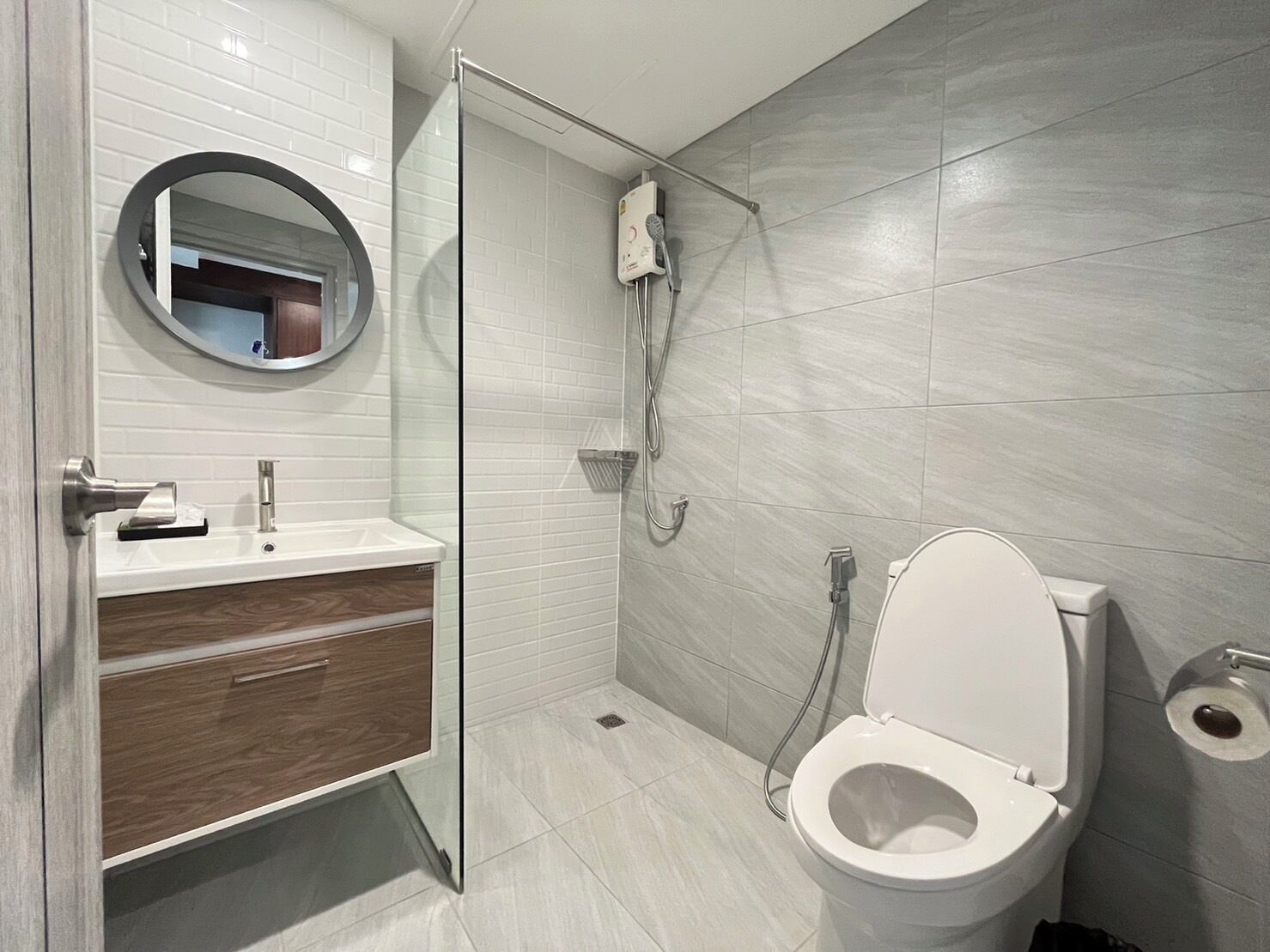A modern bathroom with a toilet, a sink with a mirror, and a shower area.
