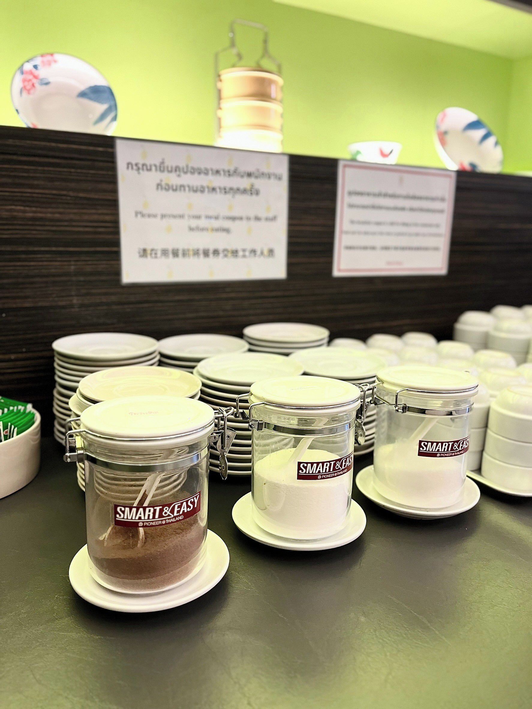 A buffet area with multiple food containers labeled 'Smart & Easy' and a sign in Thai.