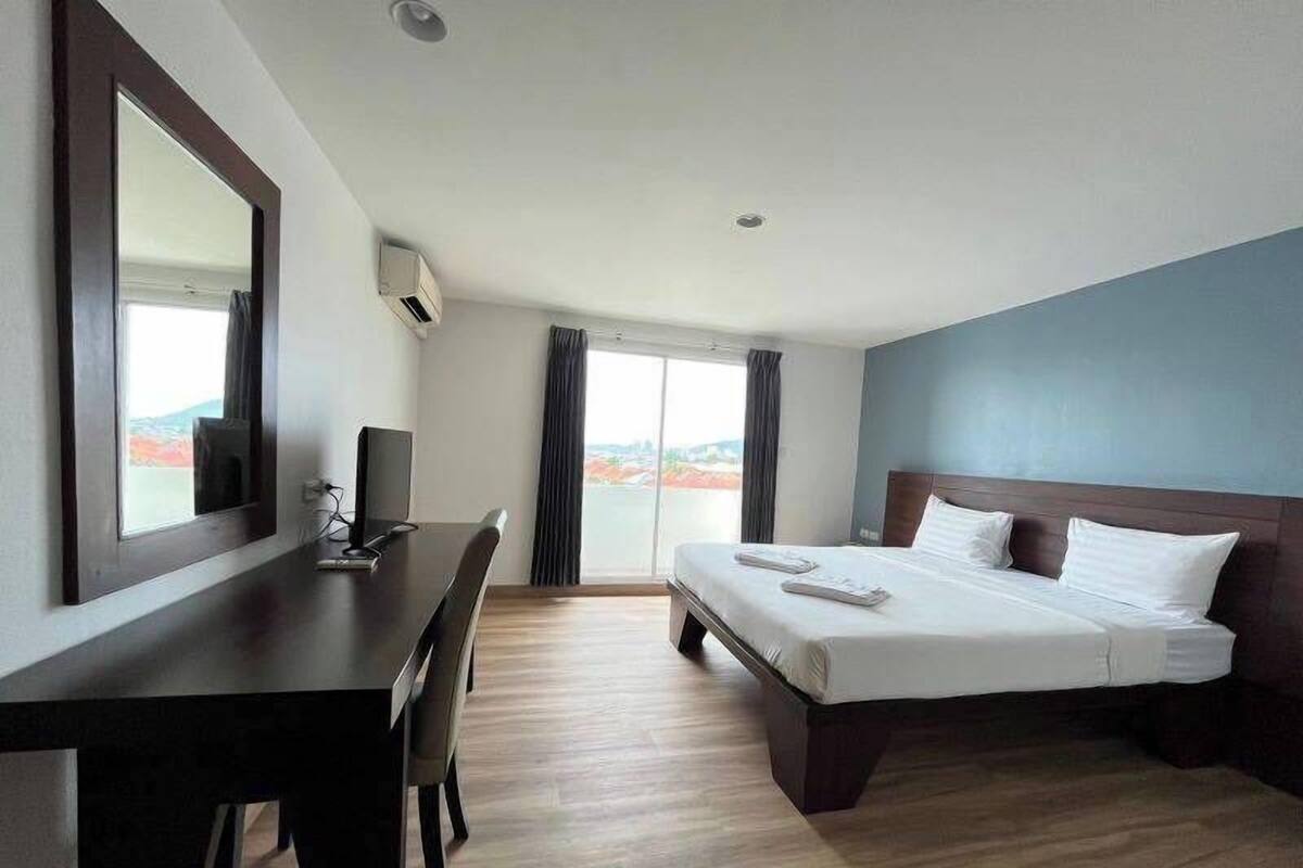 Een hotelkamer met een bed, een bureau, een stoel, een televisie en een raam met gordijnen.