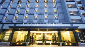 Un hôtel moderne doté d’une entrée imposante, de nombreux balcons et d’une façade bien éclairée.