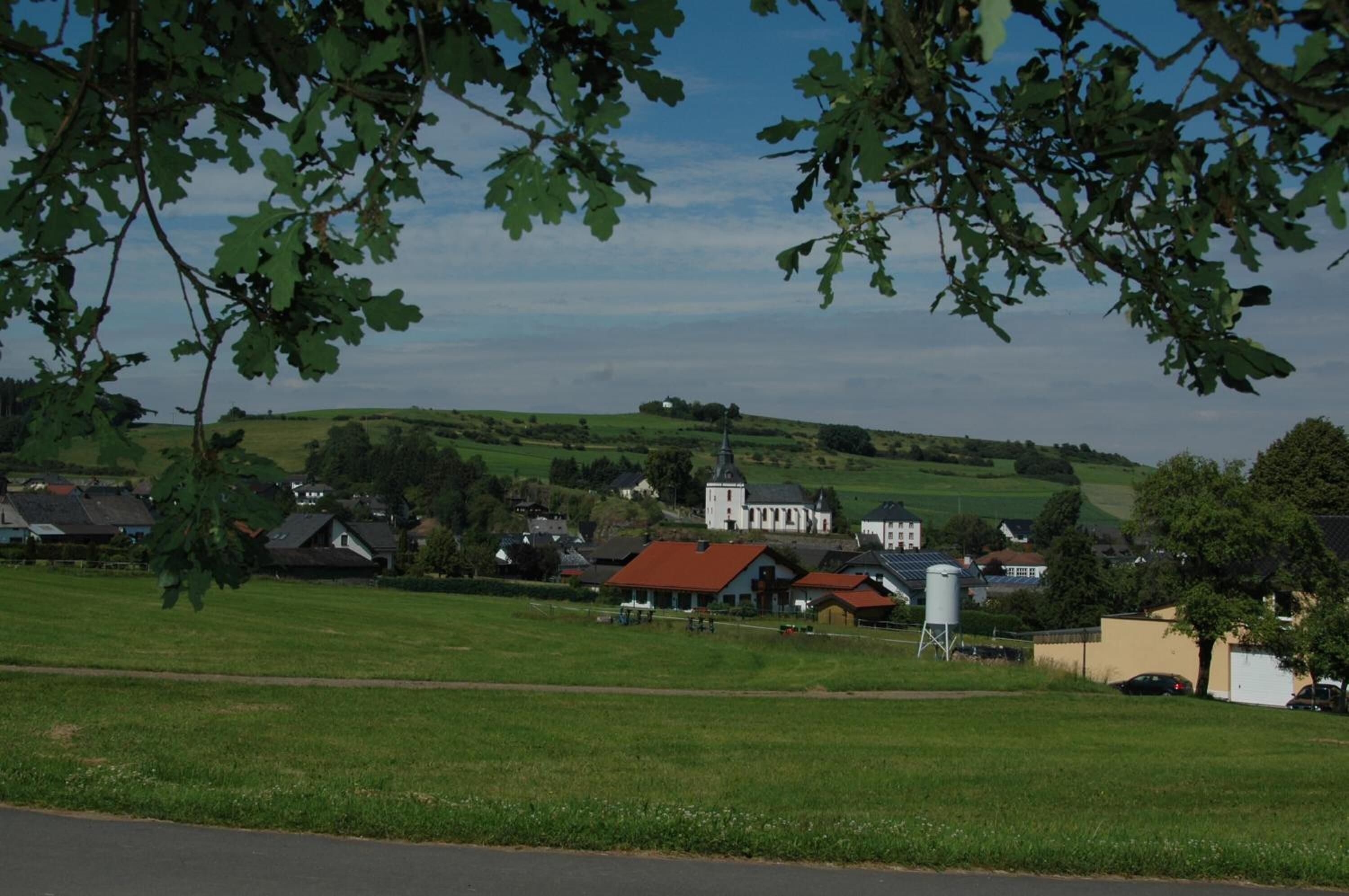 A rural landscape with houses, a church, and a water tower.