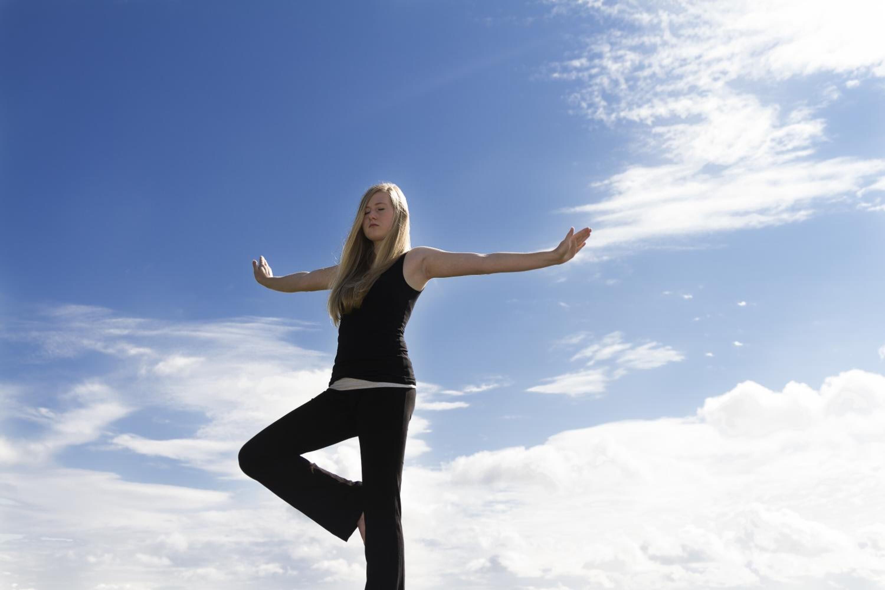 A person in a yoga pose against a clear sky.