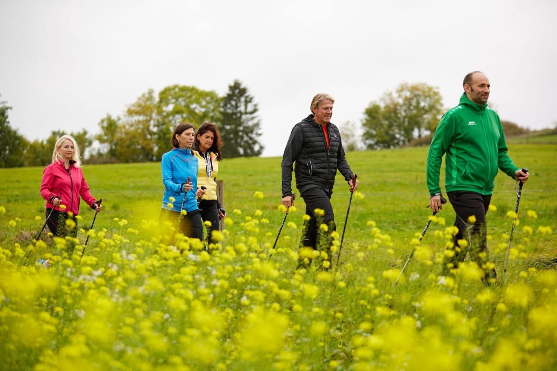 A group of people hiking in a field with yellow flowers.