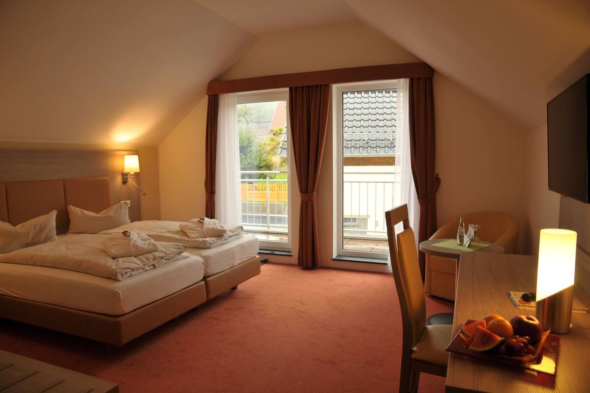 Une chambre d’hôtel avec un lit, un bureau, une chaise, une lampe et une vue sur l’extérieur.