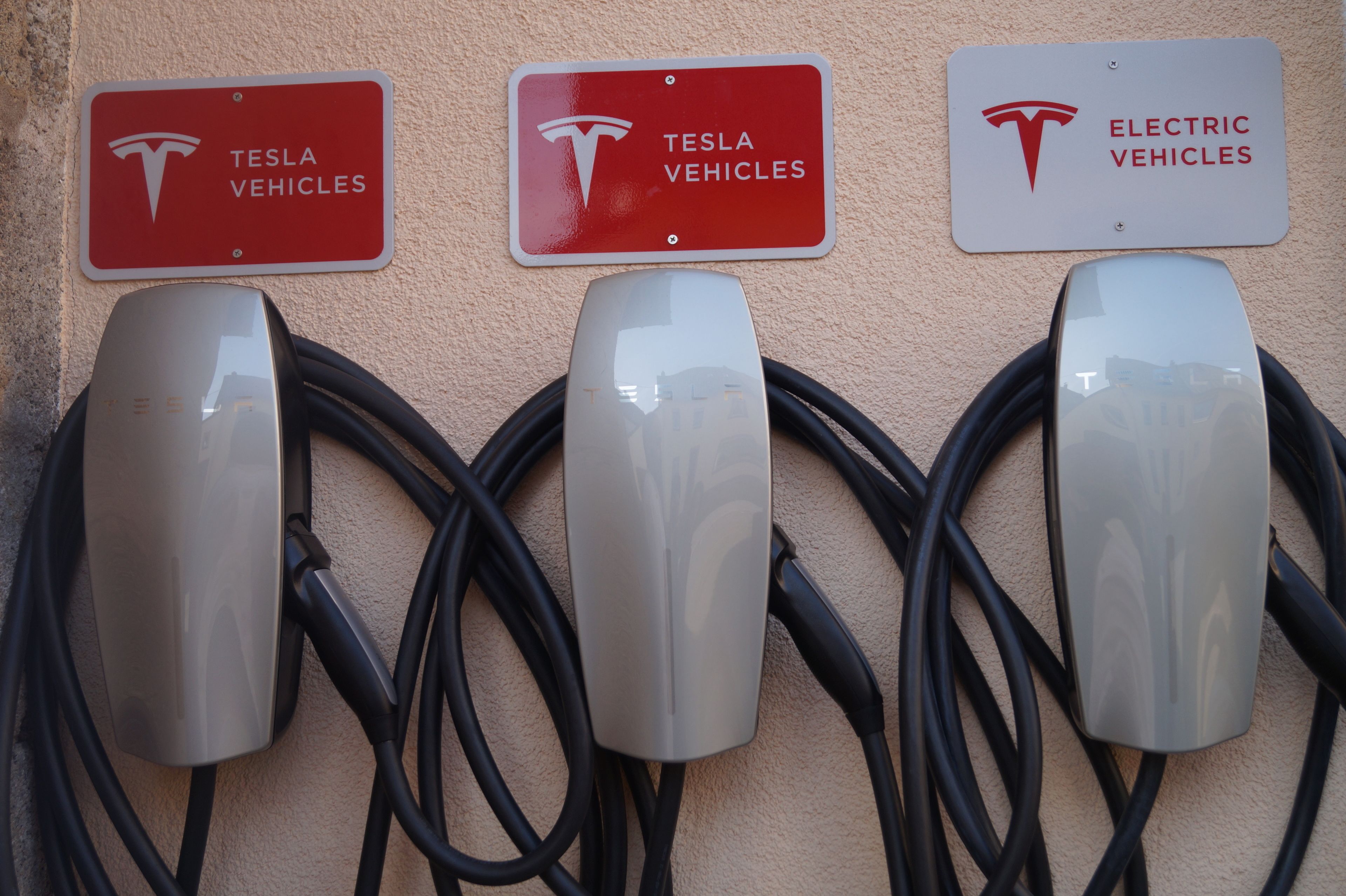 Tres estaciones de carga para Tesla con letreros rojos que indican que son solo para vehículos Tesla.