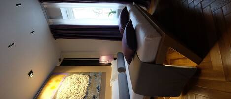 A room with a bed, a painting on the wall, a window with curtains, and a wooden floor.