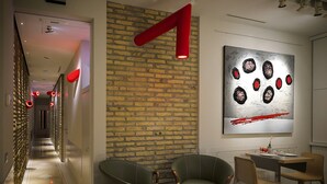 A modern interior with a brick wall, a large abstract painting, and a dining area with two chairs and a table. - Navona Rooms (Rome)