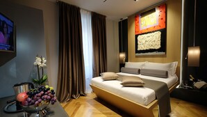 A modern hotel room with a large bed, a flat-screen TV, a fruit bowl, and a decorative wall piece. - Navona Rooms (Rome)