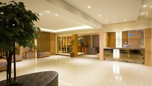 Eine geräumige Lobby mit einer Rezeption, einer Sitzecke und einer großen Pflanze in einem Topf.