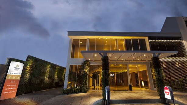Ein moderner Hotel Eingang mit Glasfassade, Empfangsbereich und Grünflächen.