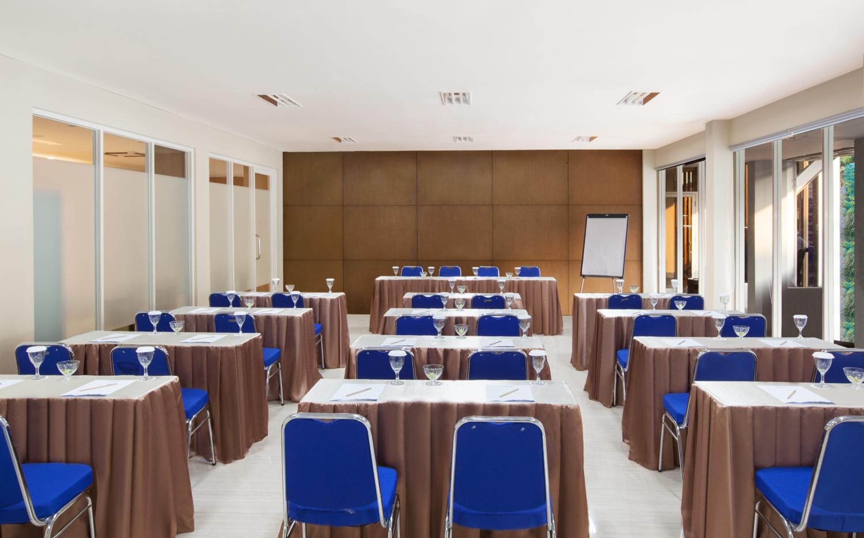 A conference room with multiple tables and chairs, a whiteboard, and large windows.