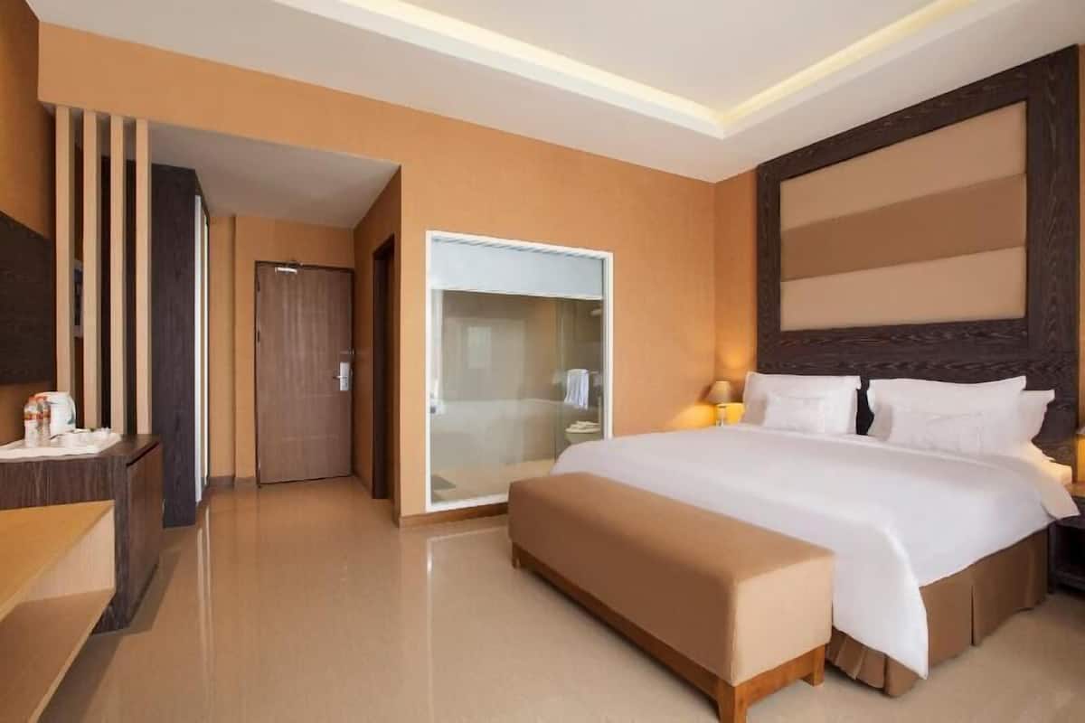 Ein Hotelzimmer mit einem großen Bett, einem Nachttisch, einem Kleiderschrank und einer Duschkabine.