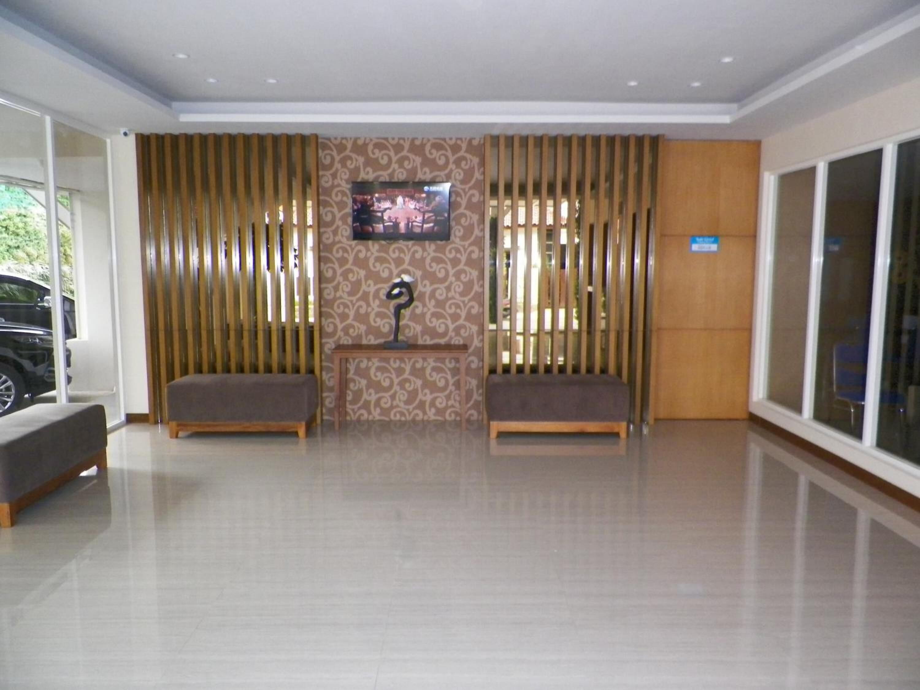 Un vestíbulo amplio con dos zonas de estar, un diseño de pared con motivos y una pantalla de televisión.