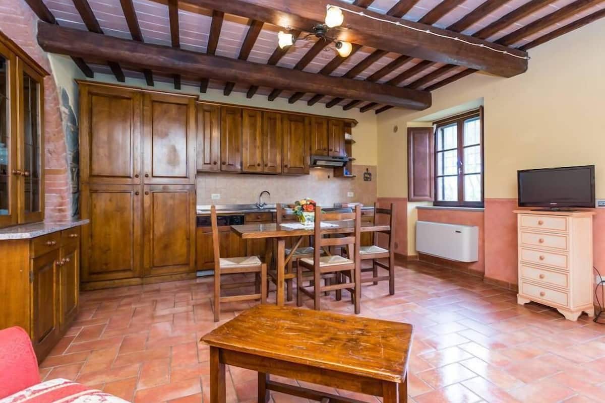 Een landelijke keuken met houten kastjes, een eettafel en stoelen.