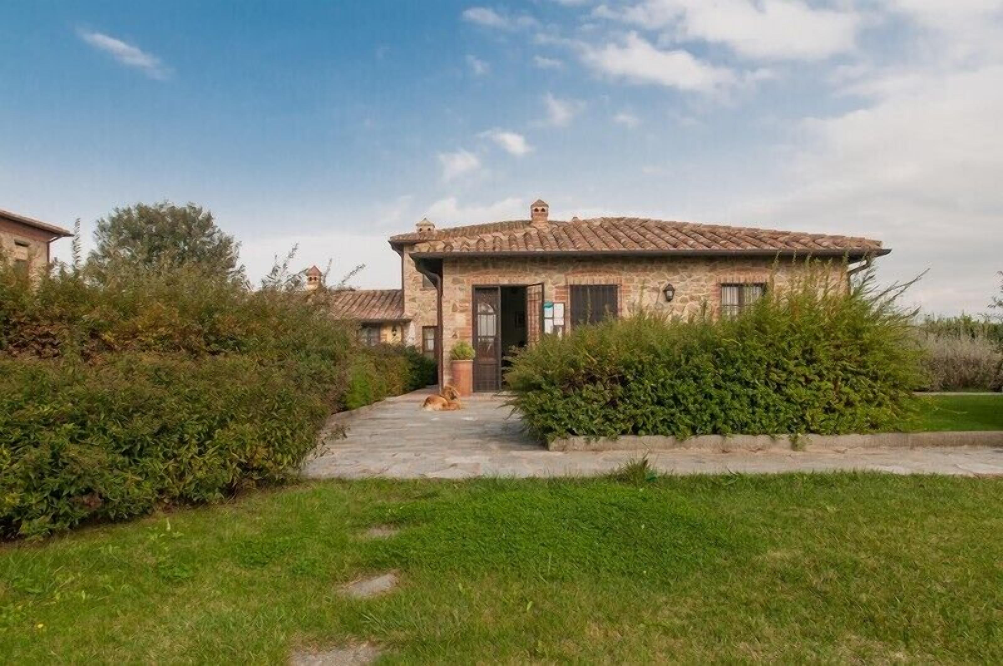 A stone building with a tiled roof, a paved entrance, and a well-maintained lawn.