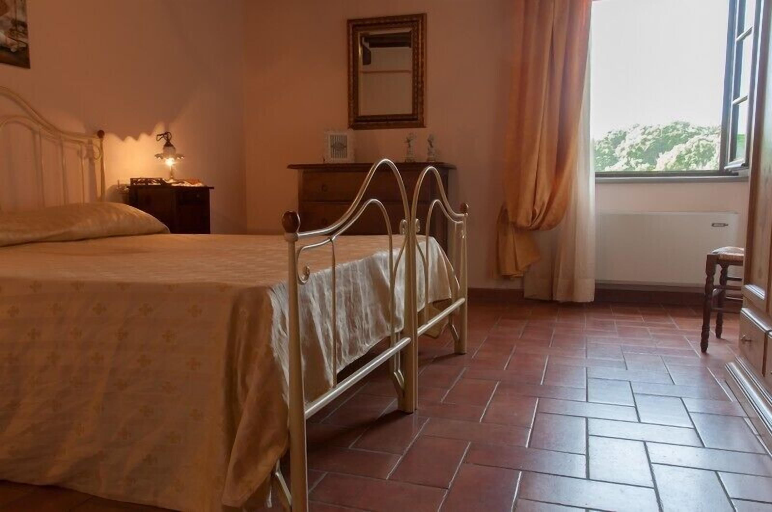 A bedroom with a bed, bedside table, dresser, and a window with curtains.