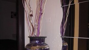 A purple vase with branches on a white wall.
