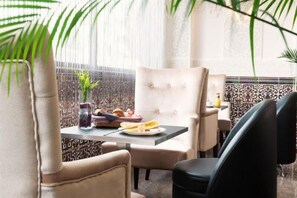 A dining area with a table set for two, featuring a variety of food items and a vase of flowers. - Hôtel Le Saint Germain (Aulnay-sous-Bois)