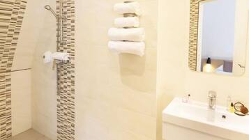 Une salle de bain avec une douche, un lavabo et un porte-serviettes.