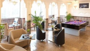 A hotel lobby with a pool table, seating area, and decorative arches.
