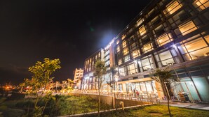 A modern building with large windows and a flat roof, surrounded by a grassy area and trees. - Tamna Stay Hotel Jeju (Jeju City)