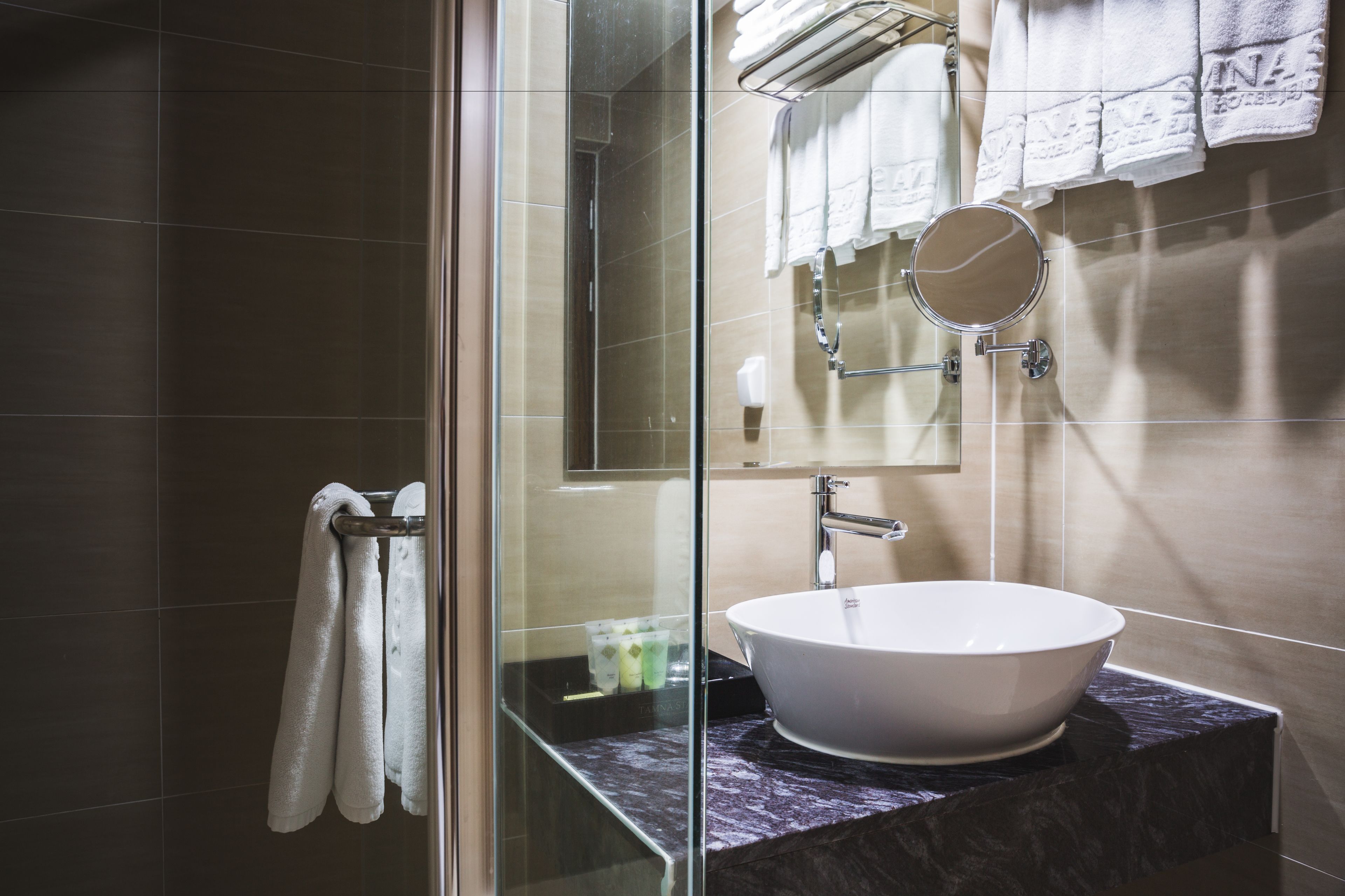 A modern bathroom with a glass shower enclosure, a white sink, and a marble countertop.
