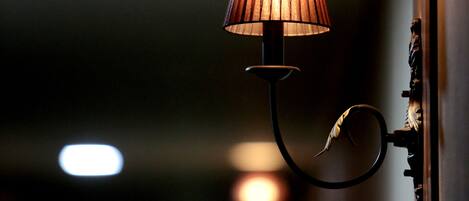 A wall-mounted lamp with a curved arm and a conical shade, positioned in a dimly lit hallway.