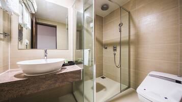 A modern bathroom with a glass-enclosed shower, a white sink, and a toilet.