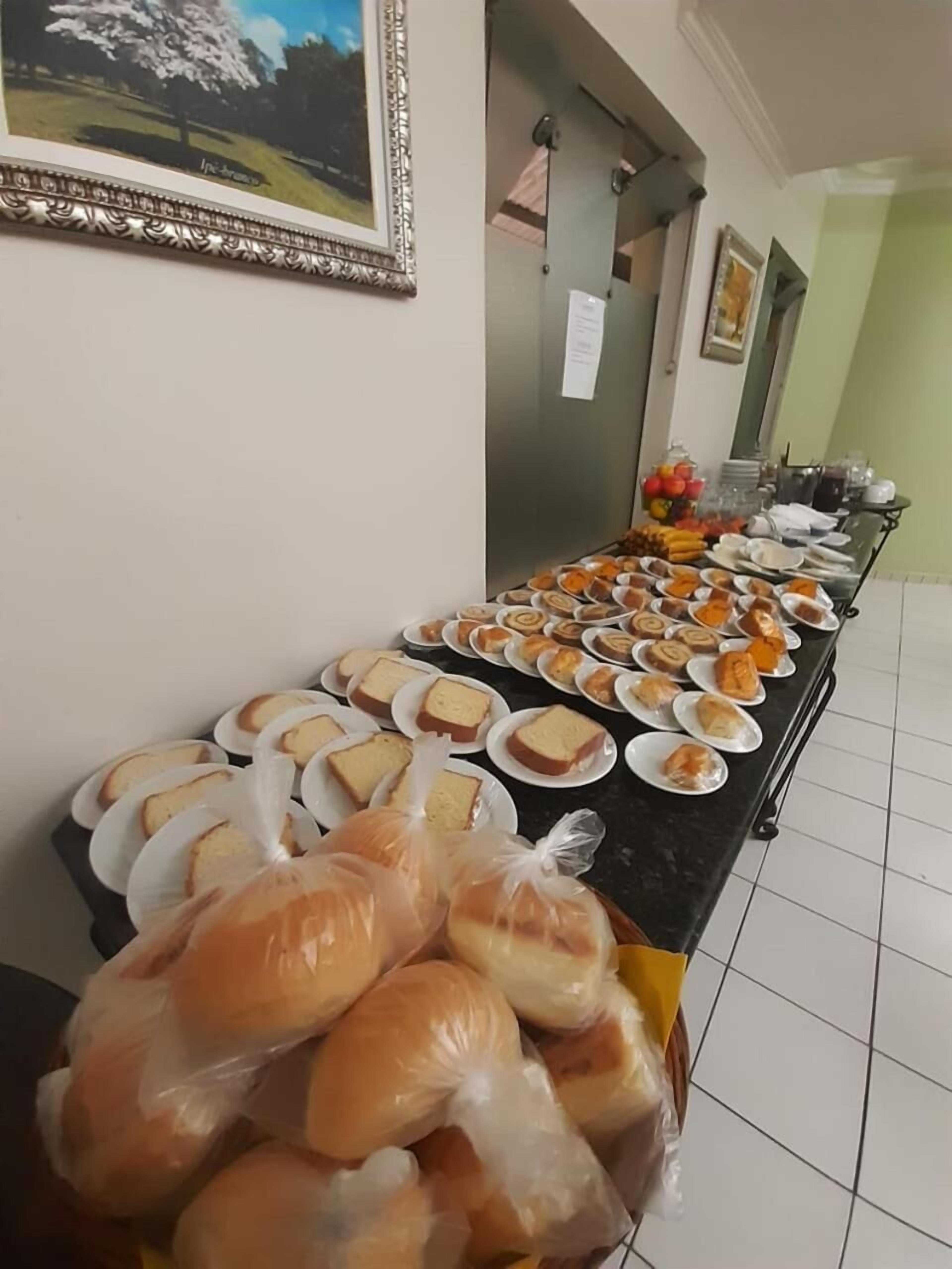 A buffet table with various pastries and bread, a framed picture on the wall, and a tiled floor.