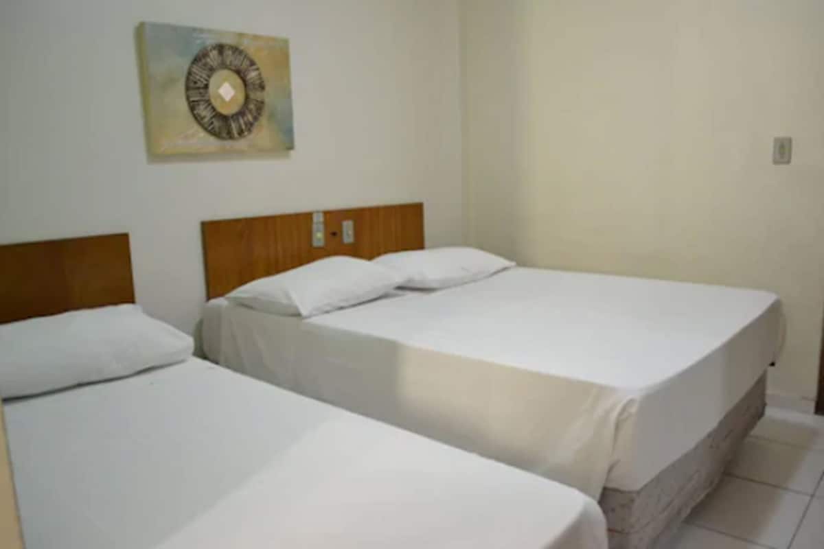 Two single beds with wooden headboards in a room with plain walls and a small decorative piece above the beds.