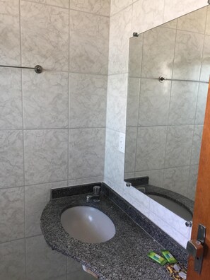 A bathroom with a marble-tiled wall, a granite countertop, a sink, and a mirror. - Hotel Ipê (Guarulhos)