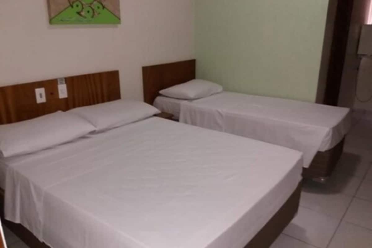 A hotel room with two single beds, a wooden headboard, and a green wall.