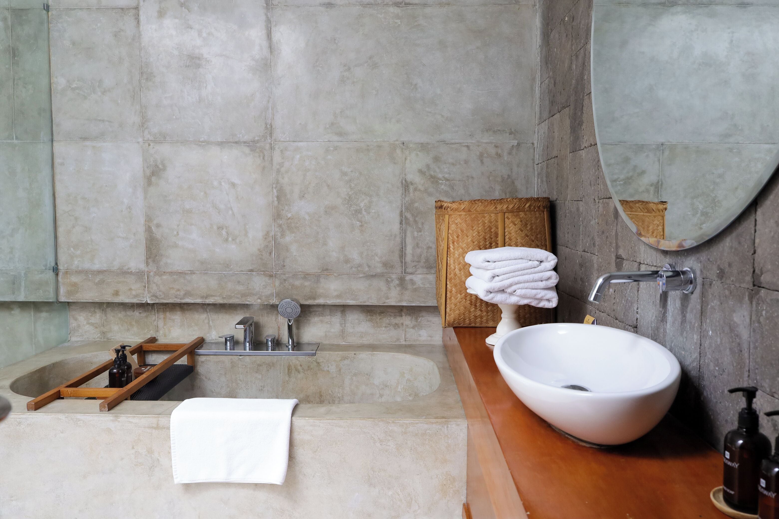 A bathroom with a bathtub, a large mirror, a sink, and neatly stacked towels.