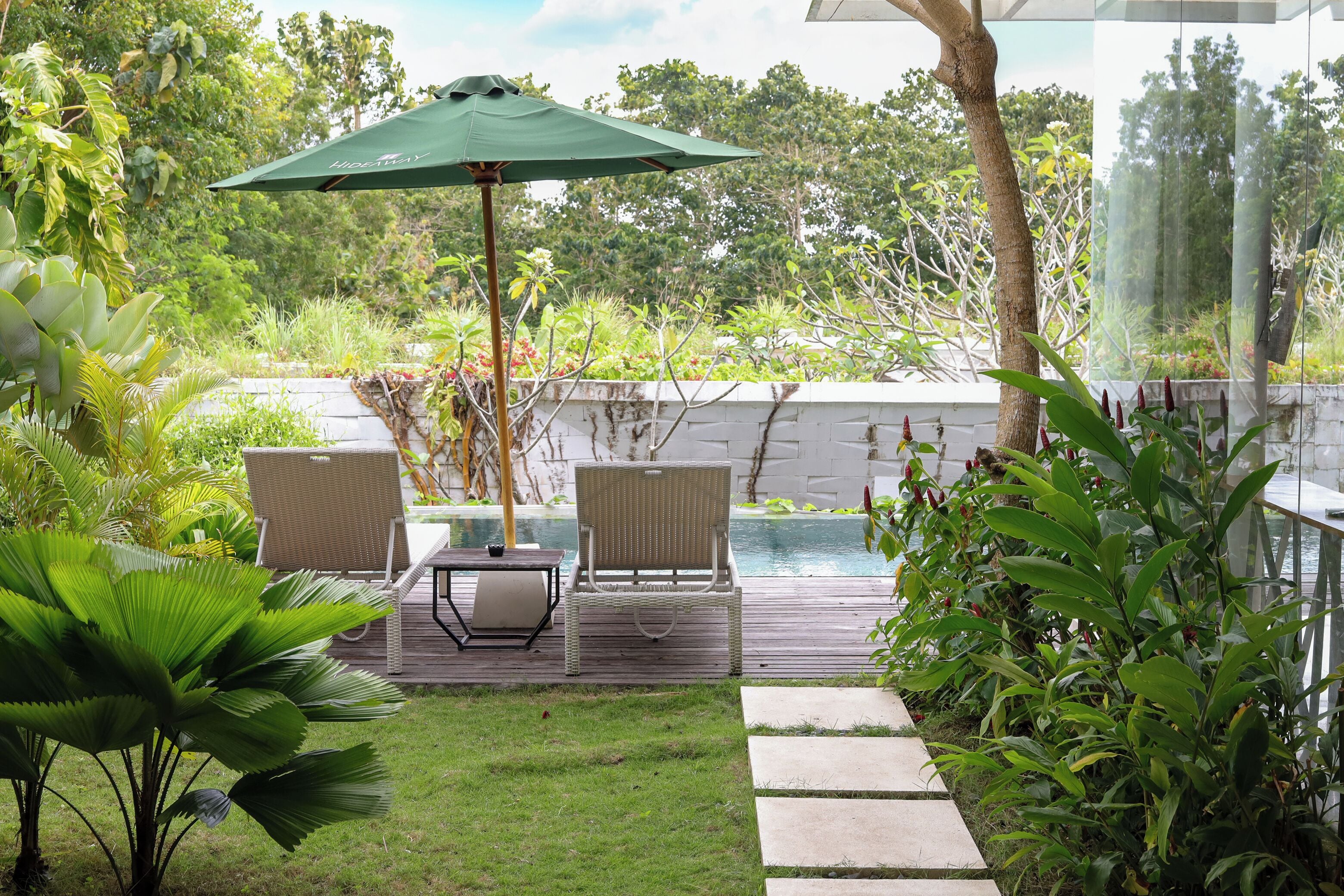 Eine Terrasse mit Gartenmöbeln, einem Pool und üppigem Grün.