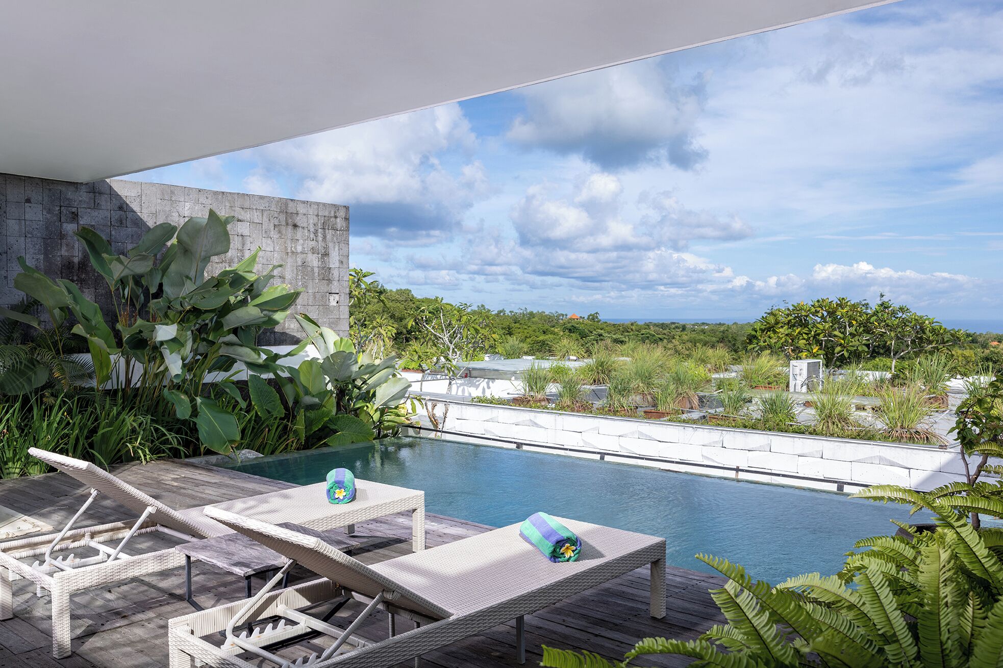 A rooftop pool area with lounge chairs and a view of the surrounding landscape.